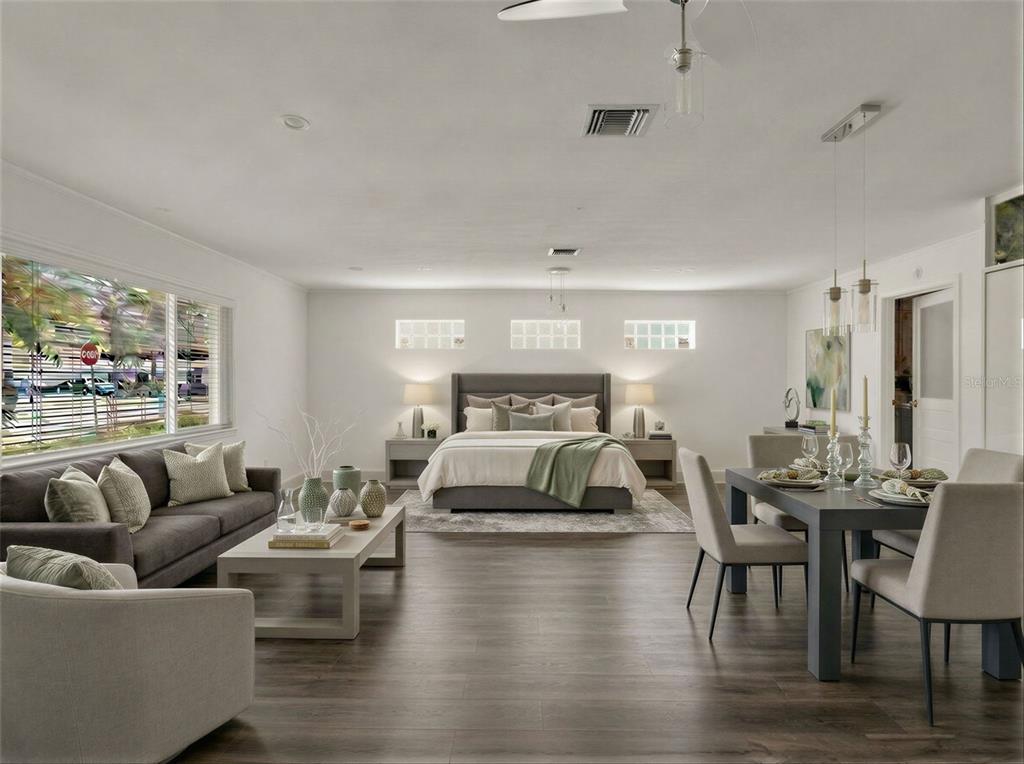 A spacious bedroom features a bed, a seating area, and a dining table on wood floors — 1231 NEWPORT AVENUE, LAKELAND, FL