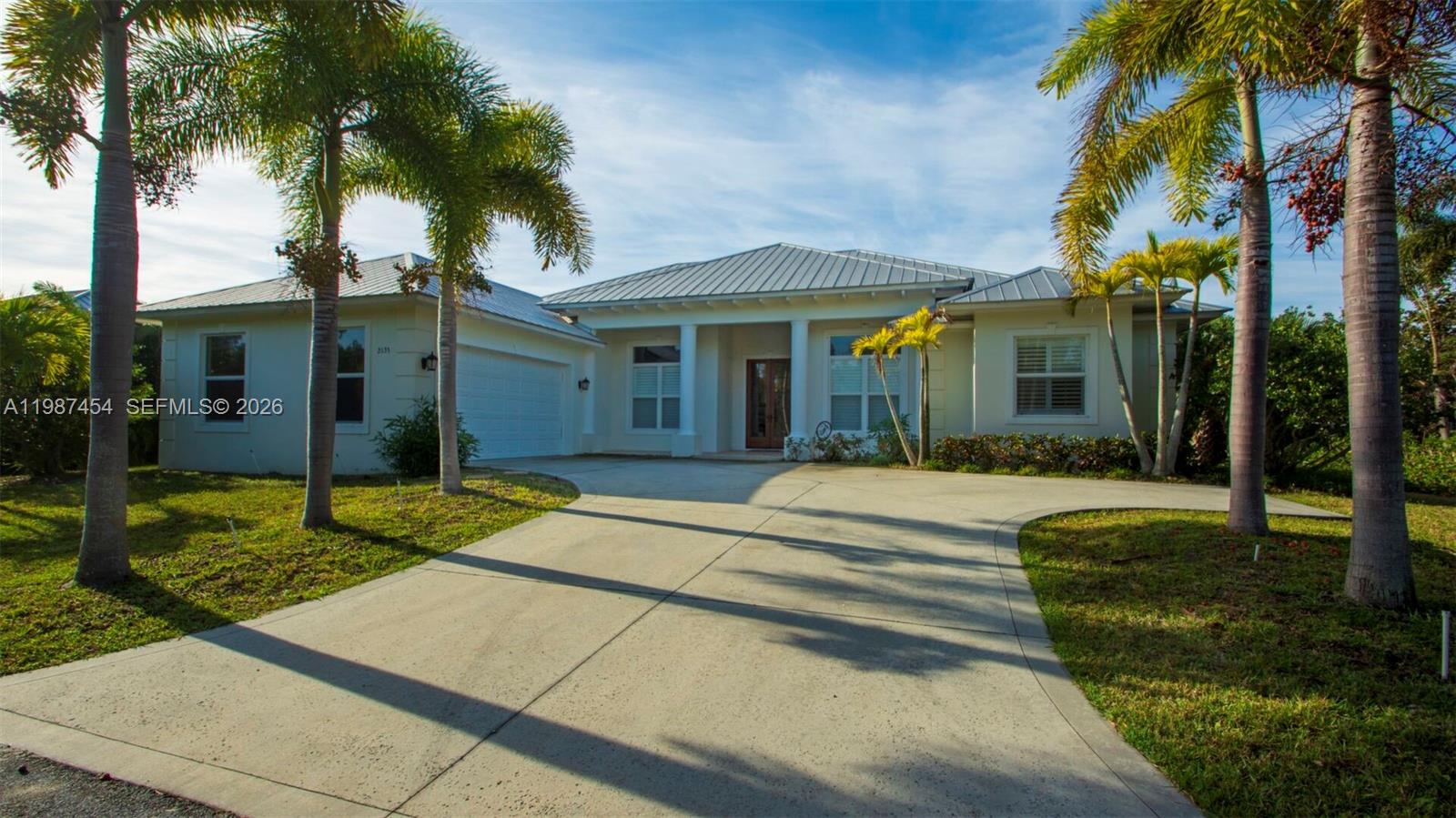 A single-story house with a metal roof, white stucco exterior, and a concrete driveway — 2135 Island Dr, Vero Beach FL 32963, VERO BEACH, FL