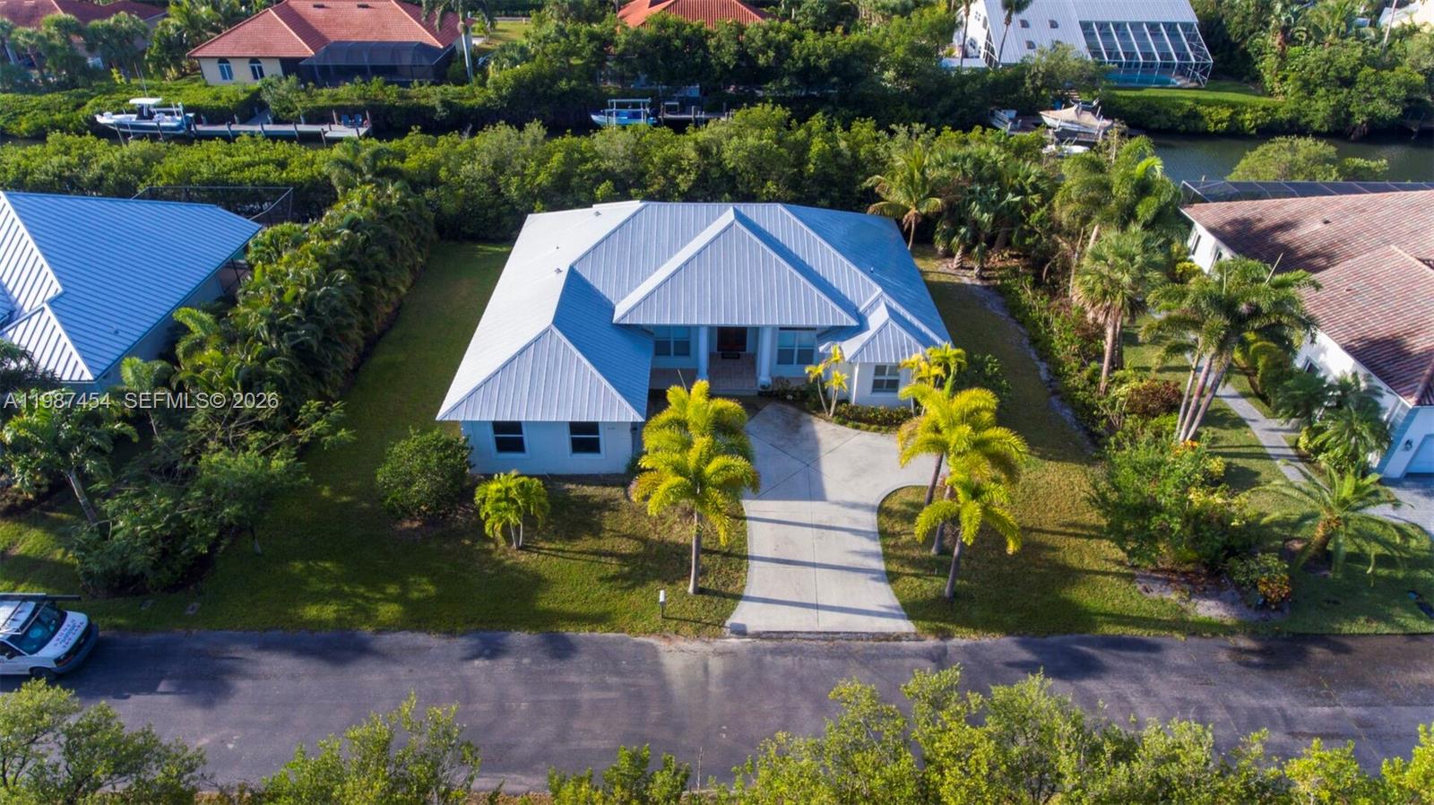 An aerial view shows a single-story house with a metal roof and a concrete driveway — 2135 Island Dr, Vero Beach FL 32963, VERO BEACH, FL