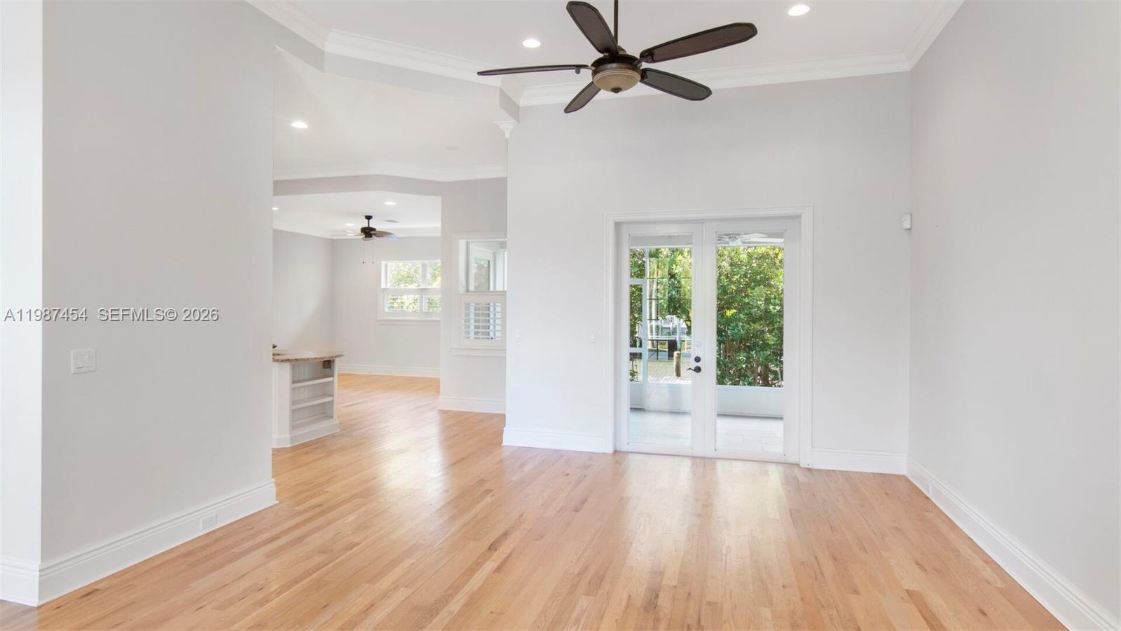 A bright living room features hardwood floors, a ceiling fan, and glass doors to a patio — 2135 Island Dr, Vero Beach FL 32963, VERO BEACH, FL