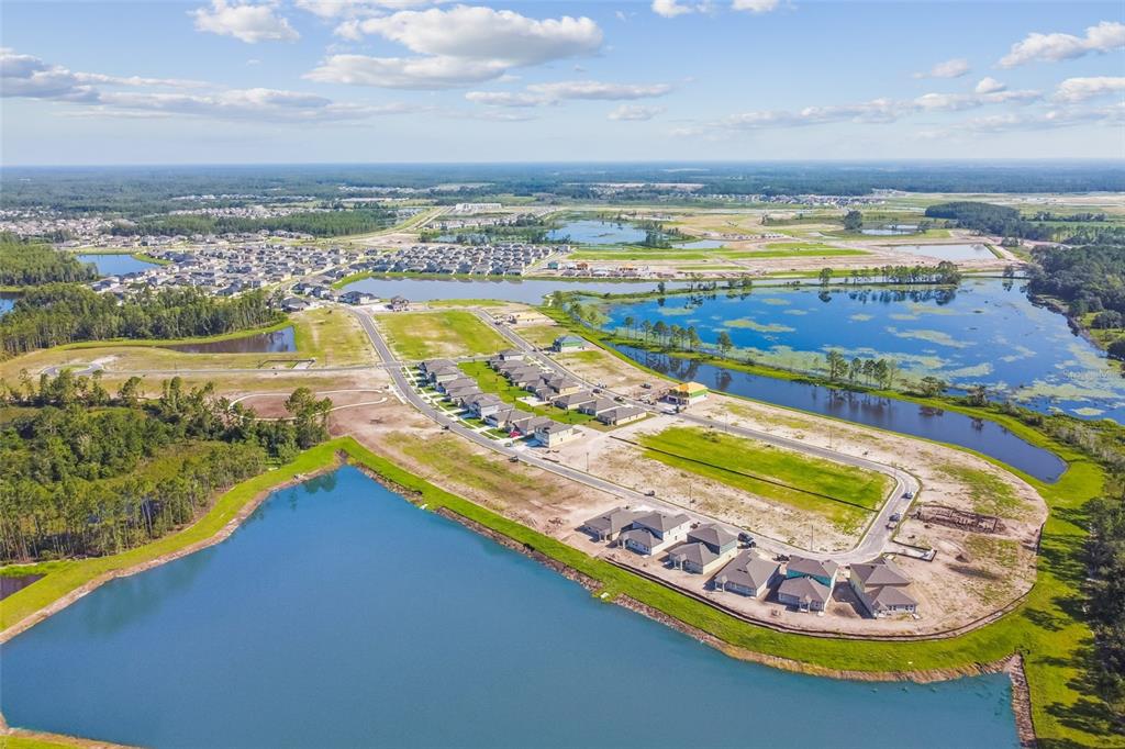 An aerial view shows a new residential development with houses bordering several large retention ponds — 7635 PAINTED SKY PLACE, LAND O LAKES, FL