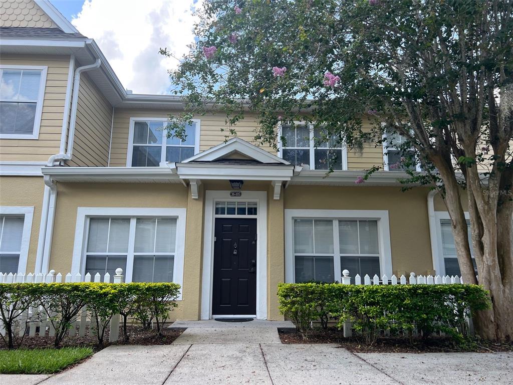 A two-story tan townhouse with a black front door and a white picket fence — 2220 SAN VITTORINO CIRCLE UNIT 105, KISSIMMEE, FL