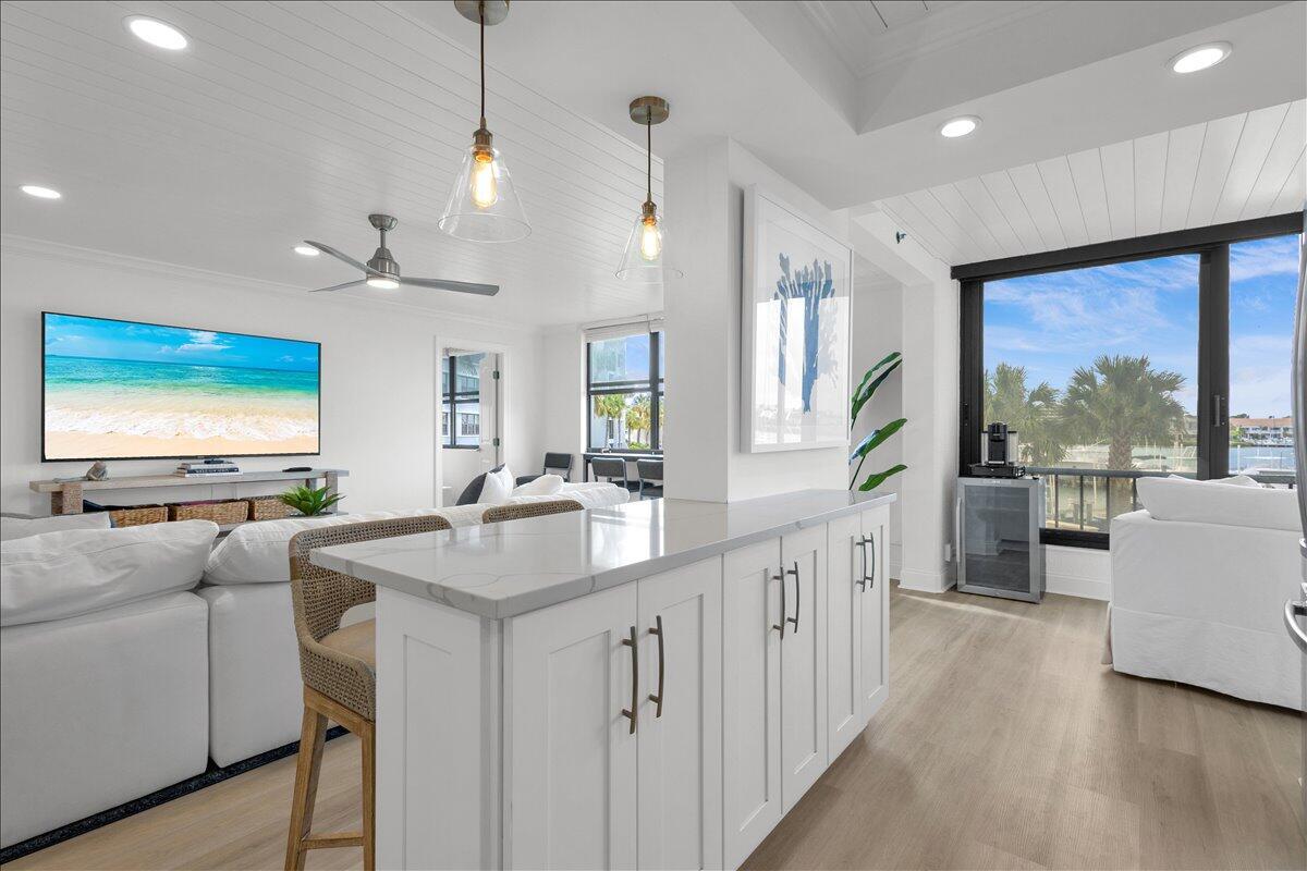 A bright kitchen island with white cabinets and quartz countertops overlooks a living area — 1648 Jupiter Cove Drive # 210, Jupiter FL 33469, JUPITER, FL