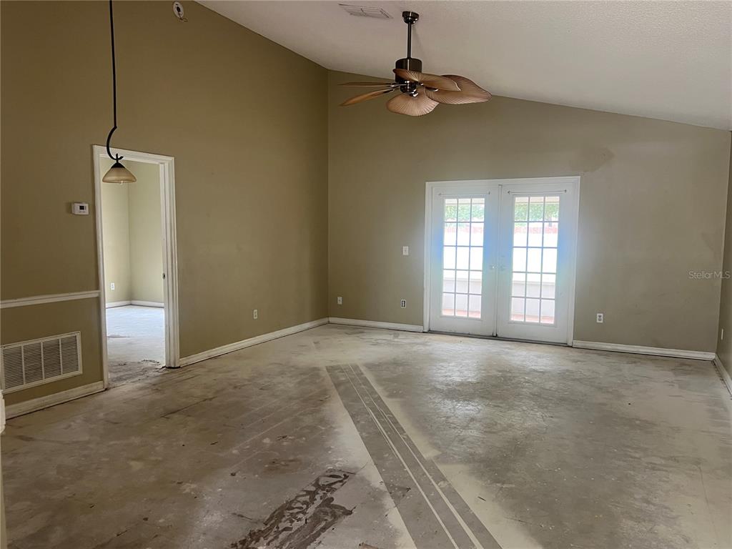 An empty room with vaulted ceilings, a ceiling fan, and unfinished concrete flooring — 1982 GREYSTONE TRAIL, ORLANDO, FL