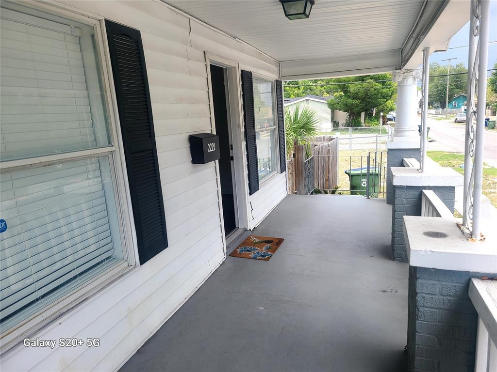 A covered front porch with white siding, black shutters, and a gray concrete floor — 2220 E 17TH AVENUE, TAMPA, FL
