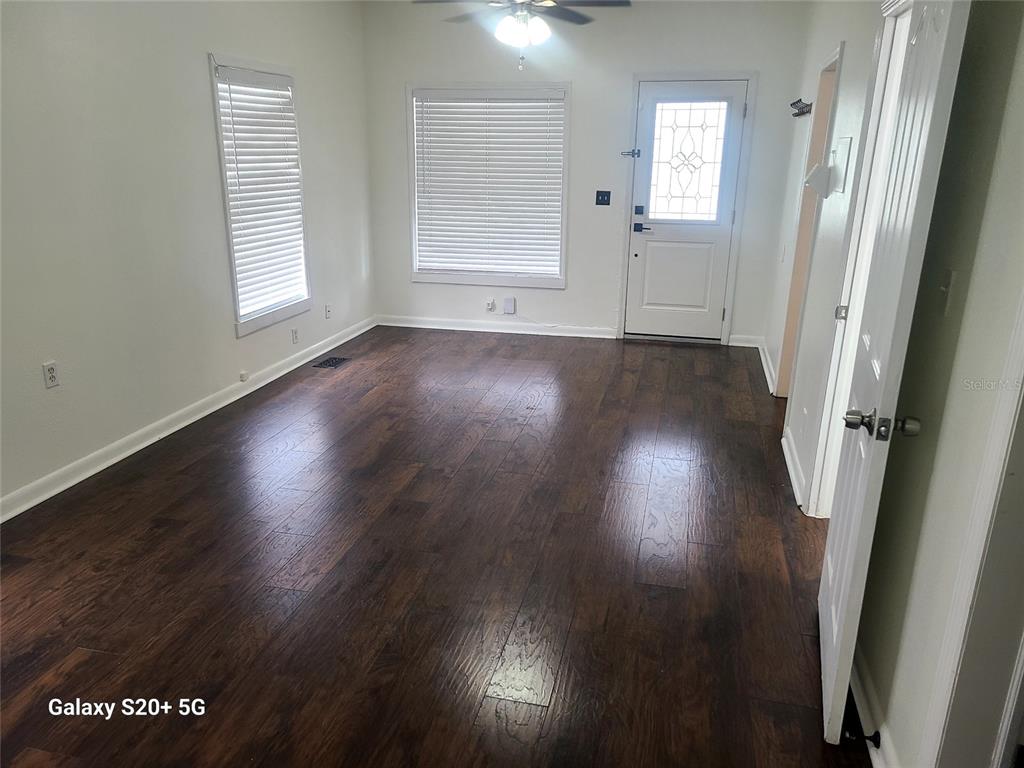 An empty room features dark wood flooring, white walls, two windows with blinds, and a door — 2220 E 17TH AVENUE, TAMPA, FL