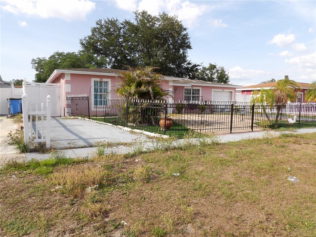 A pink, single-story house with a fenced yard and a concrete driveway — 6521 W HANNA AVENUE, TAMPA, FL