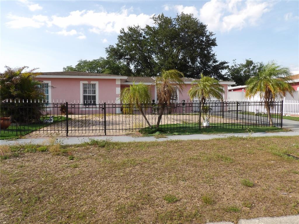 A pink single-story house with a black metal fence and palm trees in the front — 6521 W HANNA AVENUE, TAMPA, FL