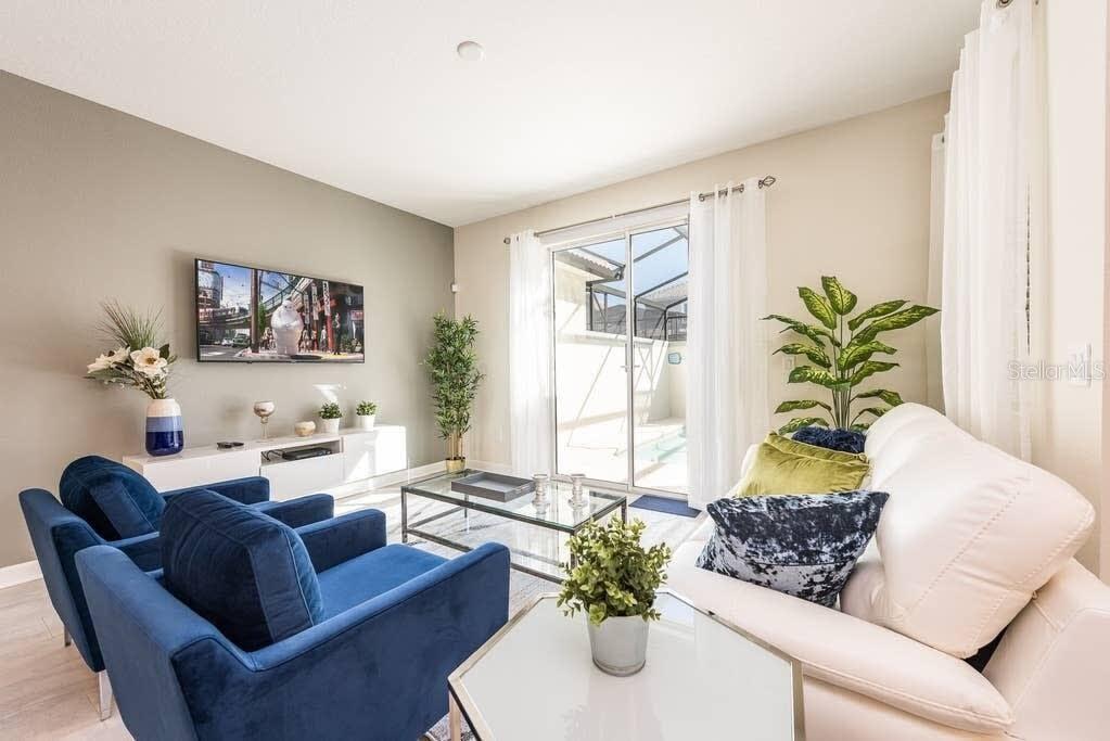 A living room features blue armchairs, a white sofa, a glass coffee table, and sliding doors — 4814 LOVE STOREY LANE, KISSIMMEE, FL