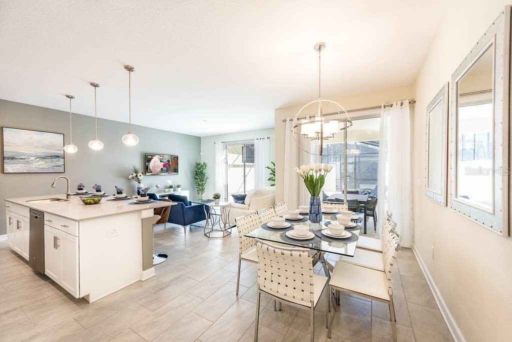 An open-concept kitchen and dining area with white cabinetry, a glass table, and tile flooring — 4814 LOVE STOREY LANE, KISSIMMEE, FL