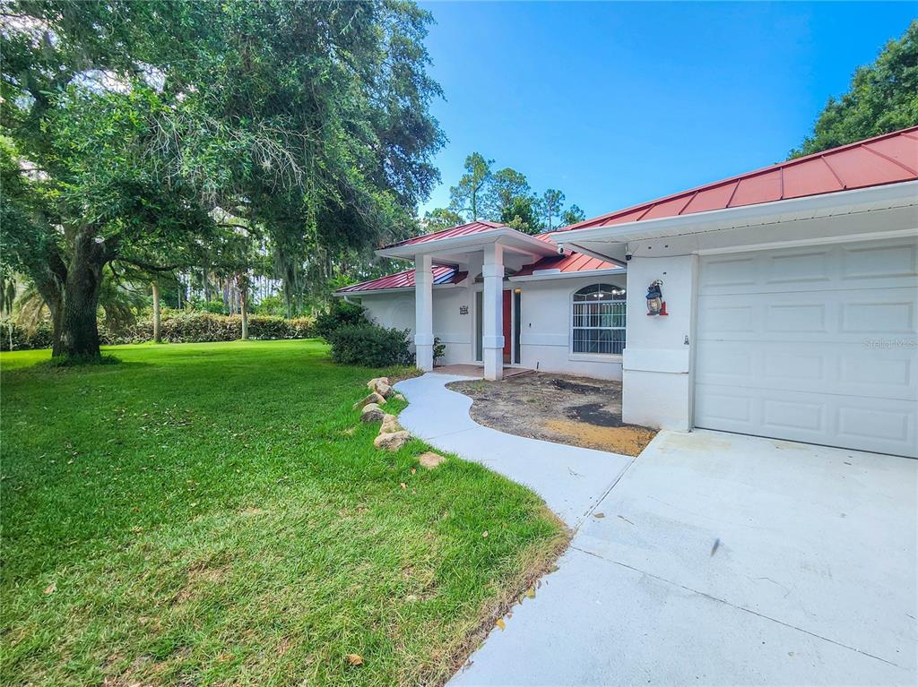 A white house with a red metal roof and a concrete driveway — 11 BUNKER HILL DRIVE, PALM COAST, FL