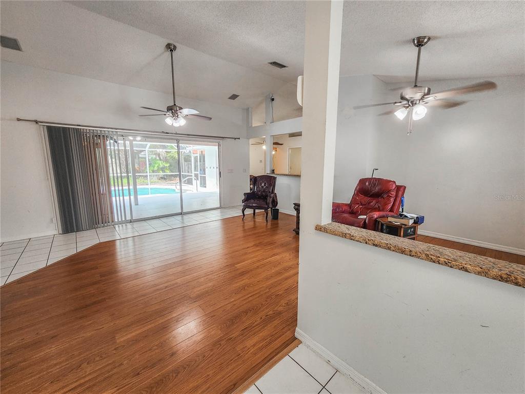 A living room with wood flooring, a ceiling fan, and a sliding door to a pool — 11 BUNKER HILL DRIVE, PALM COAST, FL