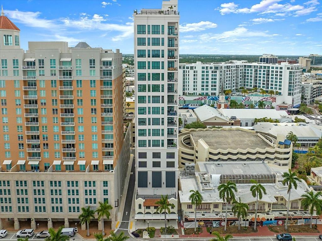 An aerial view shows a tall, narrow white residential tower situated between other city buildings — 33 S PALM AVENUE UNIT 901, SARASOTA, FL