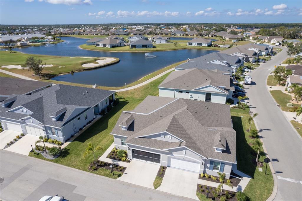 An aerial view shows suburban houses with gray roofs situated near a pond and golf course — 1755 NOTTINGHAM TRAIL, PORT CHARLOTTE, FL
