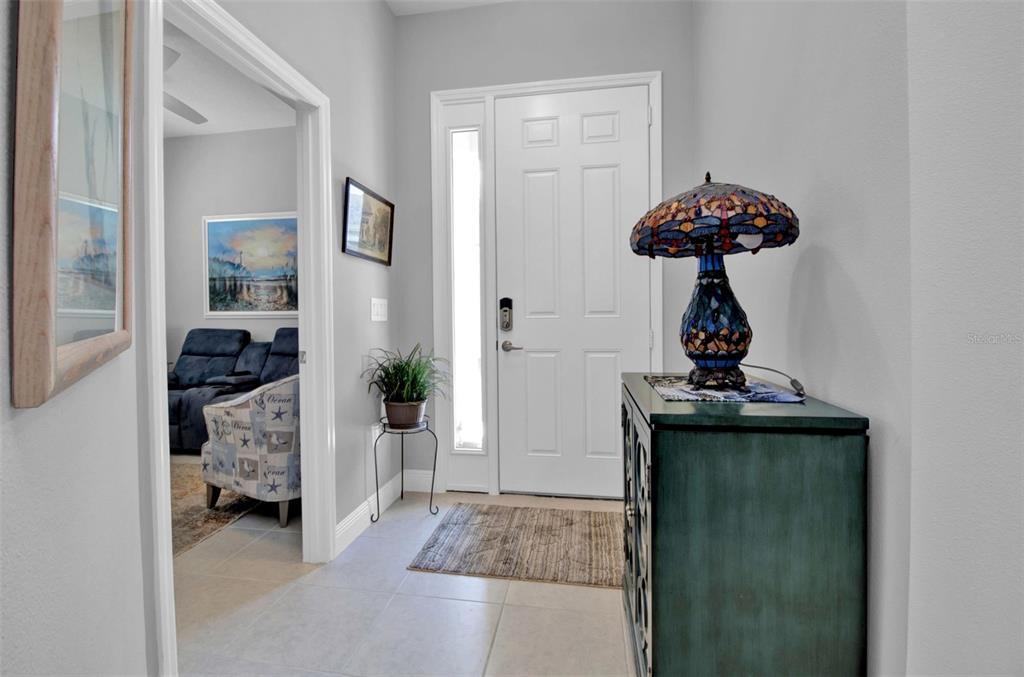 A tiled entryway features a white front door, a decorative lamp, and a side room — 1755 NOTTINGHAM TRAIL, PORT CHARLOTTE, FL