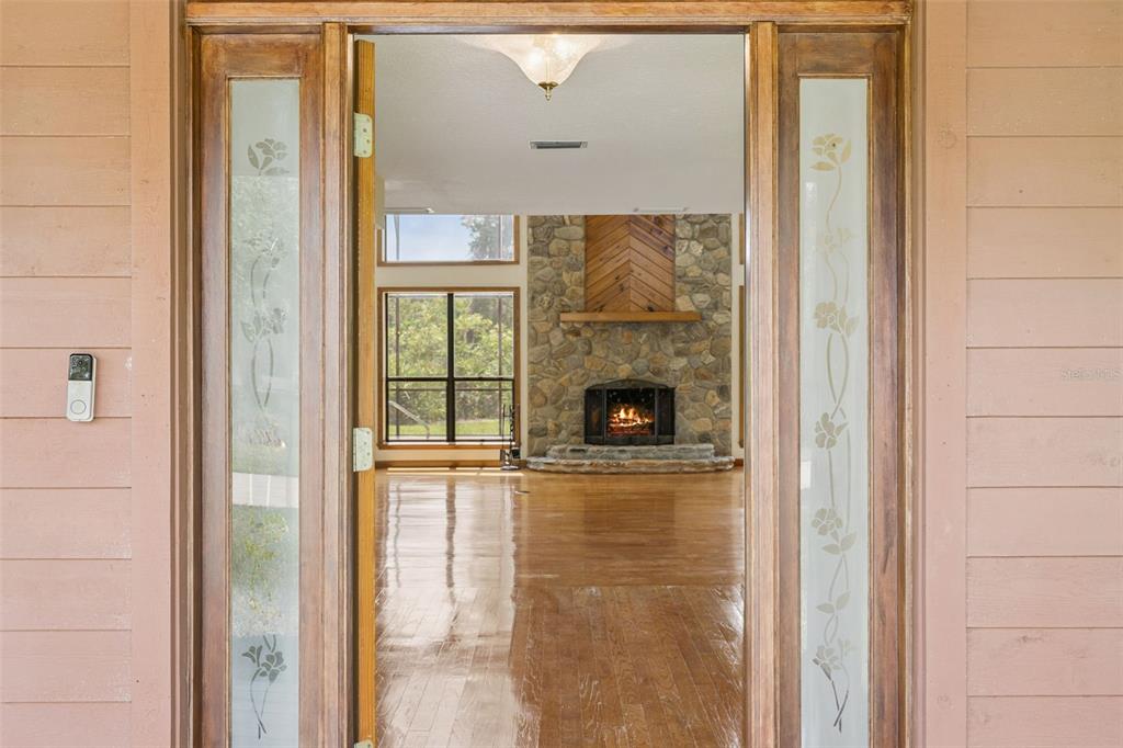 A view through an open front door reveals a living room with a stone fireplace — 15010 MILL POND ROAD, TAVARES, FL