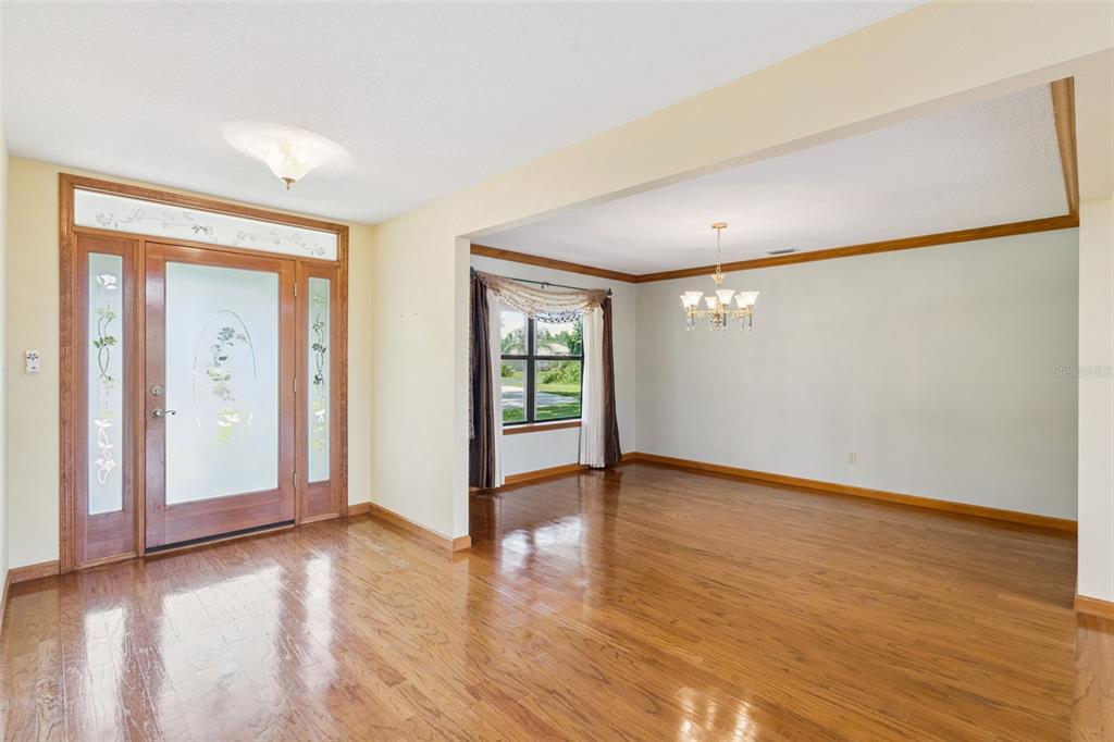 An entryway with hardwood floors leads into a dining room featuring a chandelier and window — 15010 MILL POND ROAD, TAVARES, FL