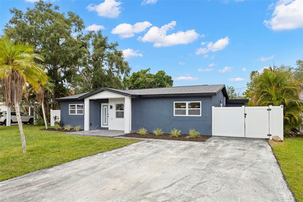 A dark gray single-story house features a white front door, driveway, and a white fence — 4430 CARSON STREET NE, ST PETERSBURG, FL