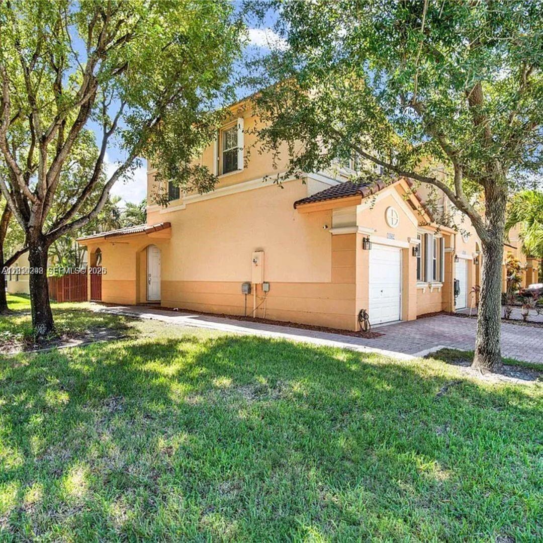A two-story stucco townhouse with a single-car garage and a paved driveway — 10902 NW 79th St # 10902, Doral FL 33178, DORAL, FL