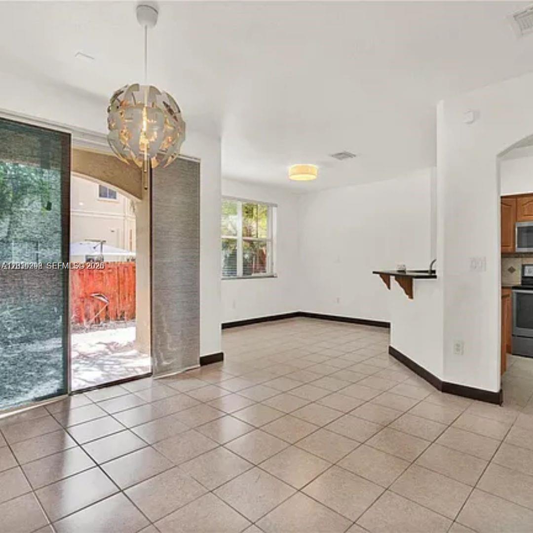 A dining area with tile flooring, a modern pendant light, and a sliding glass door — 10902 NW 79th St # 10902, Doral FL 33178, DORAL, FL