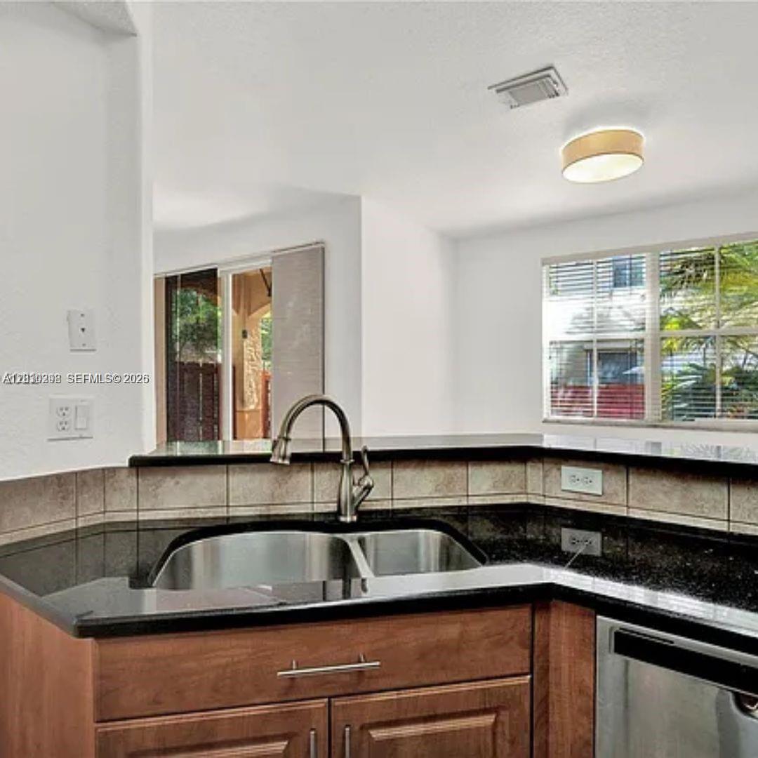 A kitchen sink with a stainless steel faucet sits in a black granite countertop — 10902 NW 79th St # 10902, Doral FL 33178, DORAL, FL