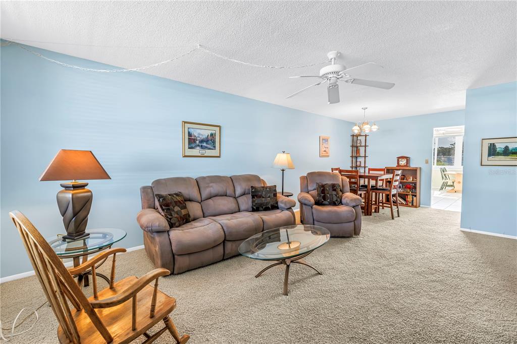 A living room with a brown sofa, recliner, glass coffee table, and light blue walls — 4715 BAY STREET NE UNIT 320, ST PETERSBURG, FL