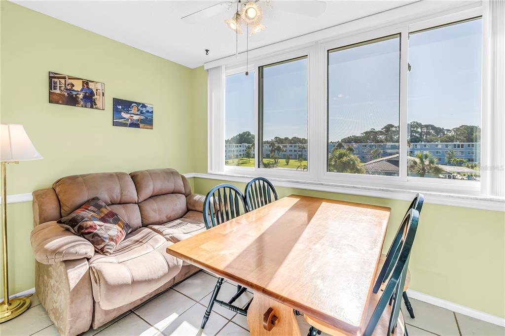 A dining area with a tan sofa, wooden table, dark chairs, and large windows — 4715 BAY STREET NE UNIT 320, ST PETERSBURG, FL
