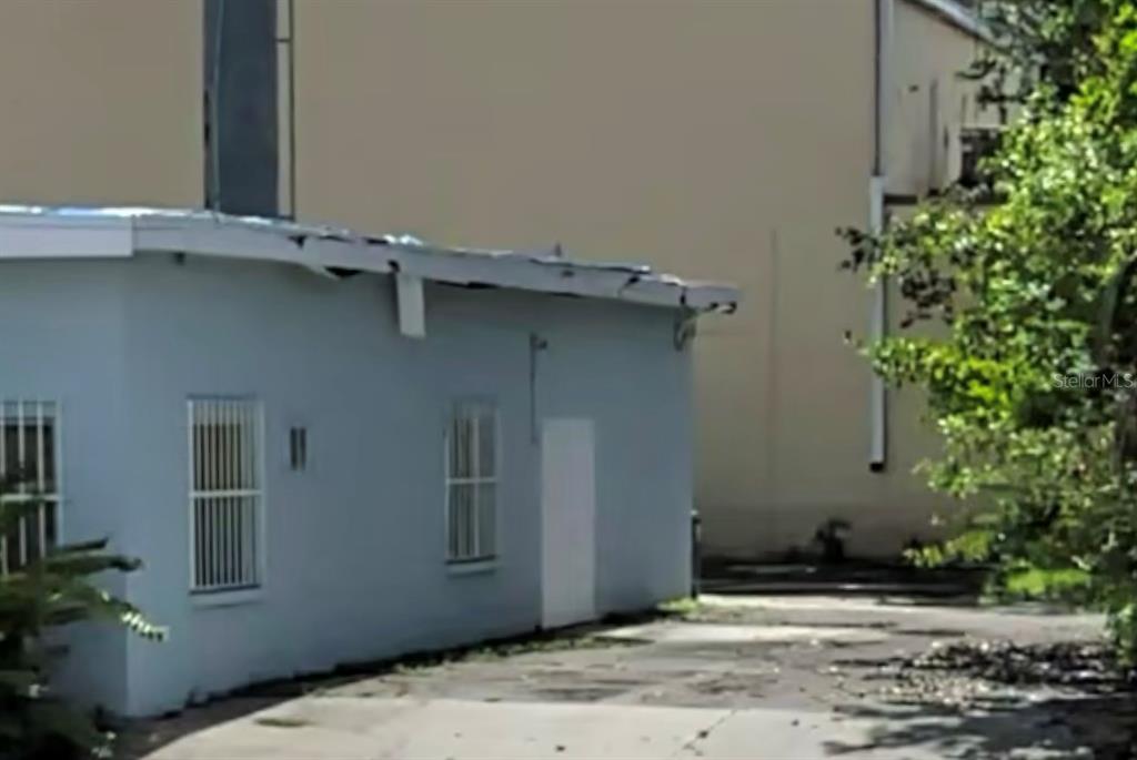 A light blue exterior wall of a building features two windows with security bars — 904 7TH AVENUE E, BRADENTON, FL