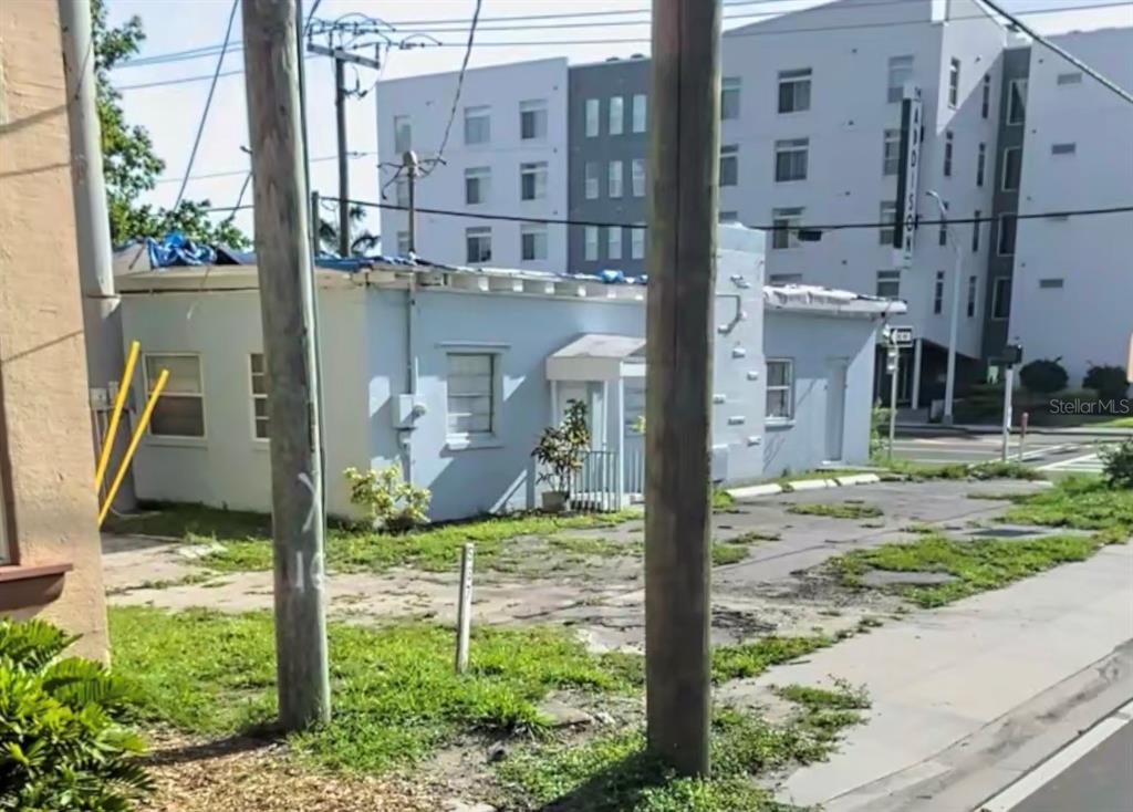A small, light-blue single-story building sits next to a large, modern multi-story apartment complex — 904 7TH AVENUE E, BRADENTON, FL