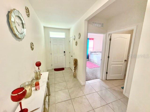 A tiled entryway features a white console table, a wall clock, and two interior doors — 3728 ALDER BARK LANE, SANFORD, FL