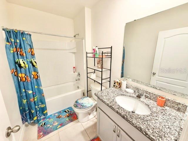 A bathroom features a fish-patterned shower curtain, a granite vanity, and a toilet with shelving — 3728 ALDER BARK LANE, SANFORD, FL