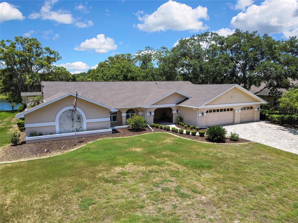 An aerial view of a tan, single-story house with a three-car garage and lawn — 4293 RIVER BIRCH DRIVE, SPRING HILL, FL