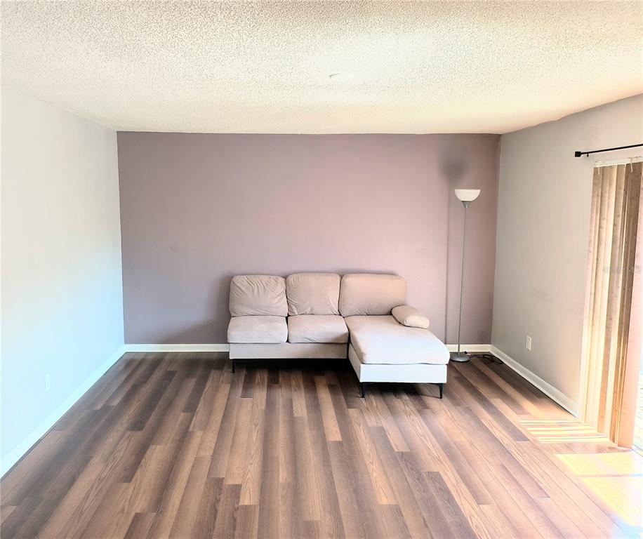A living room features a light-colored sectional sofa, a floor lamp, and wood-look flooring — 201 S ARRAWANA AVENUE UNIT L, TAMPA, FL