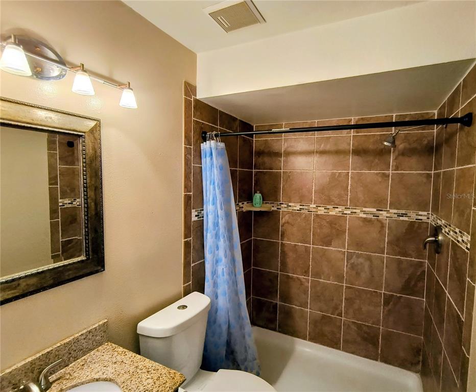 A bathroom features a tiled shower-tub combination, a toilet, and a vanity with a mirror — 201 S ARRAWANA AVENUE UNIT L, TAMPA, FL