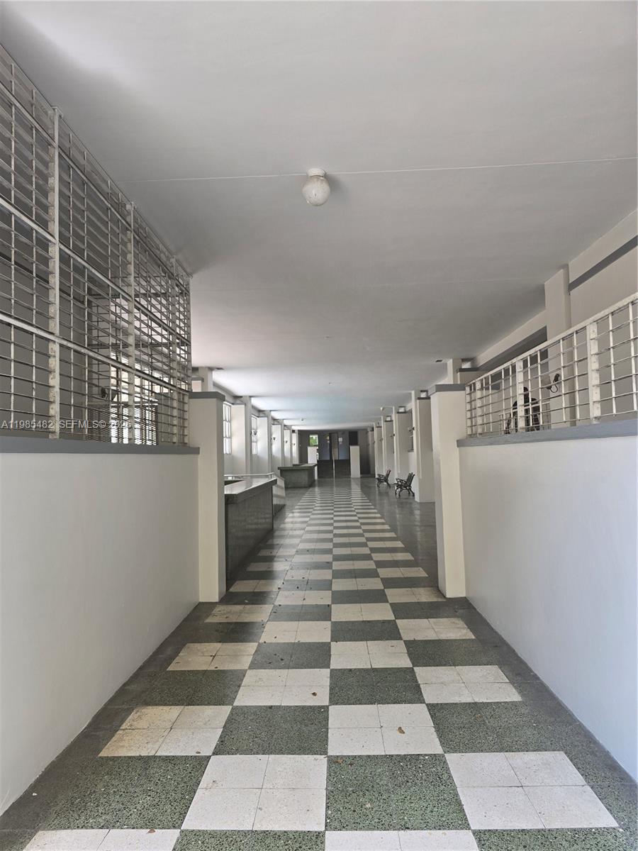 A long, covered outdoor walkway features a checkered tile floor and metal security grilles — 7420 W 20th Ave # 451, Hialeah FL 33016, HIALEAH, FL