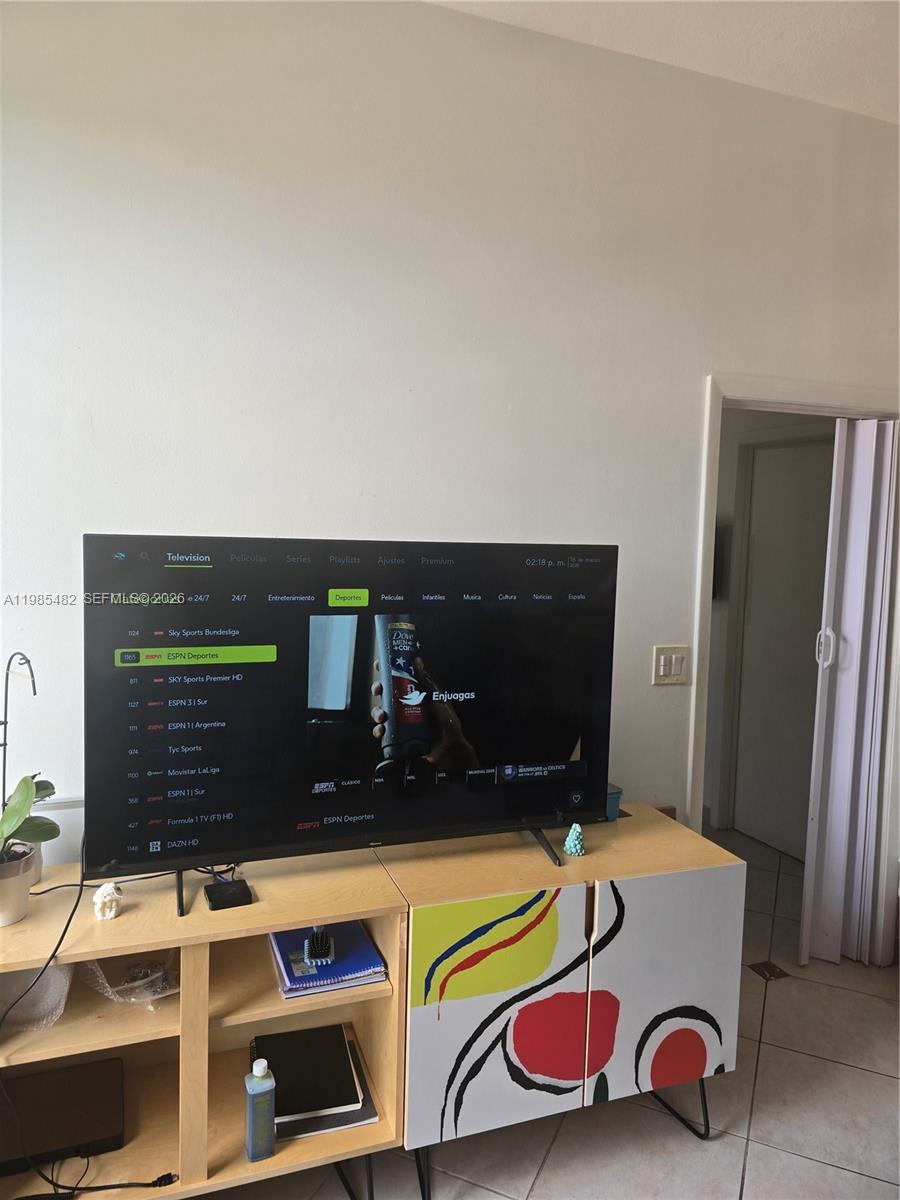 A television sits on a cabinet with a colorful abstract design in a living room — 7420 W 20th Ave # 451, Hialeah FL 33016, HIALEAH, FL