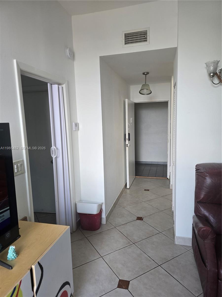 A tiled hallway connects a living area to an entryway with a white door — 7420 W 20th Ave # 451, Hialeah FL 33016, HIALEAH, FL