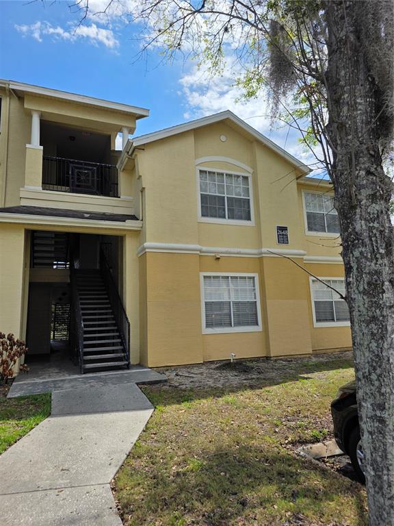 A two-story yellow apartment building features an exterior staircase and a concrete walkway — 2648 ROBERT TRENT JONES DRIVE UNIT 227, ORLANDO, FL