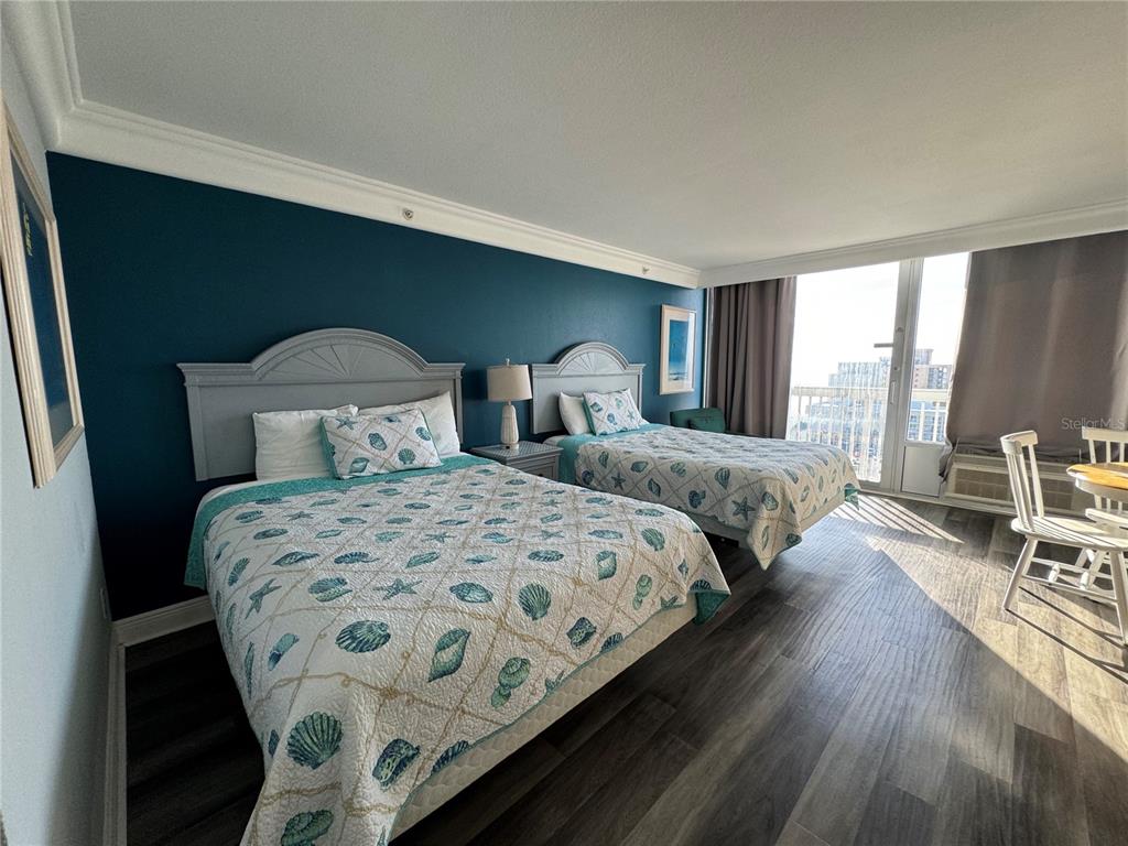 A bedroom features two beds with seashell-patterned quilts against a dark blue accent wall — 2700 N ATLANTIC AVENUE UNIT 1003, DAYTONA BEACH, FL