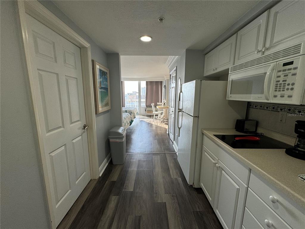 A galley kitchen with white cabinets leads into a bedroom with a view of the ocean — 2700 N ATLANTIC AVENUE UNIT 1003, DAYTONA BEACH, FL