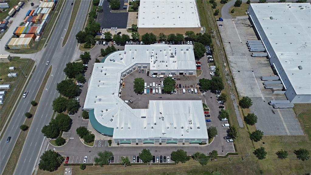 An aerial view shows a commercial building complex with a central parking lot and surrounding roads — 10501 S ORANGE AVENUE UNIT 107, ORLANDO, FL