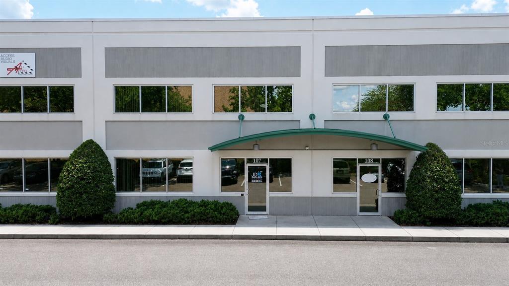 A two-story commercial building exterior features a green awning over two glass entrance doors — 10501 S ORANGE AVENUE UNIT 107, ORLANDO, FL