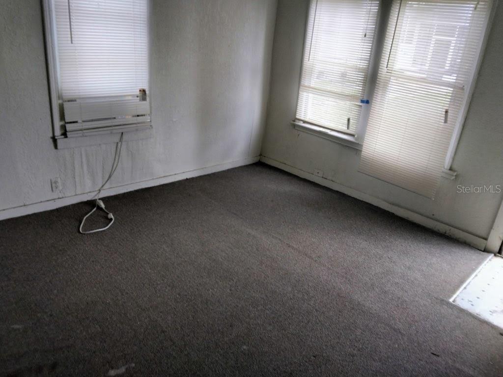 An empty bedroom features gray carpet, white walls, and windows with closed horizontal blinds — 1102 W 13TH STREET, LAKELAND, FL
