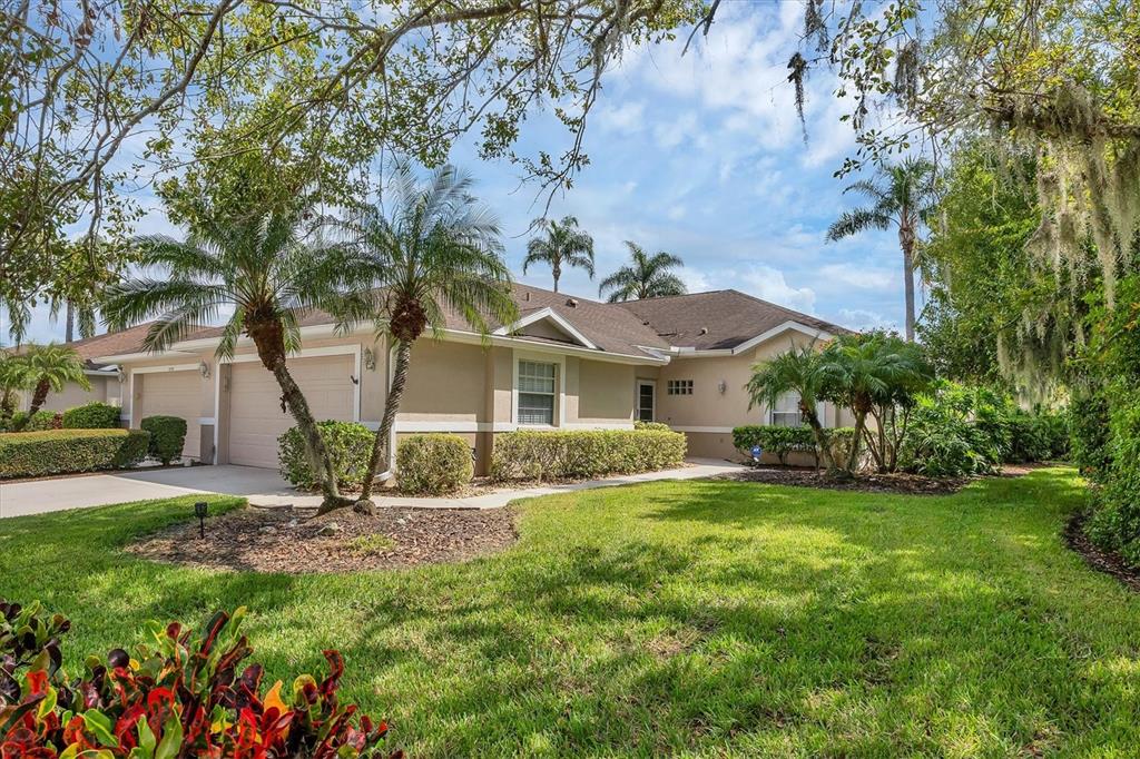 A single-story beige house with a two-car garage, palm trees, and a landscaped front lawn — 5111 PEPPERMILL COURT, SARASOTA, FL