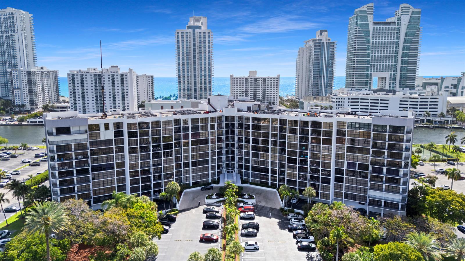 An aerial view shows a large multi-story apartment building with a parking lot in front — 600 Parkview Drive # 823, Hallandale Beach FL 33009, HALLANDALE BEACH, FL