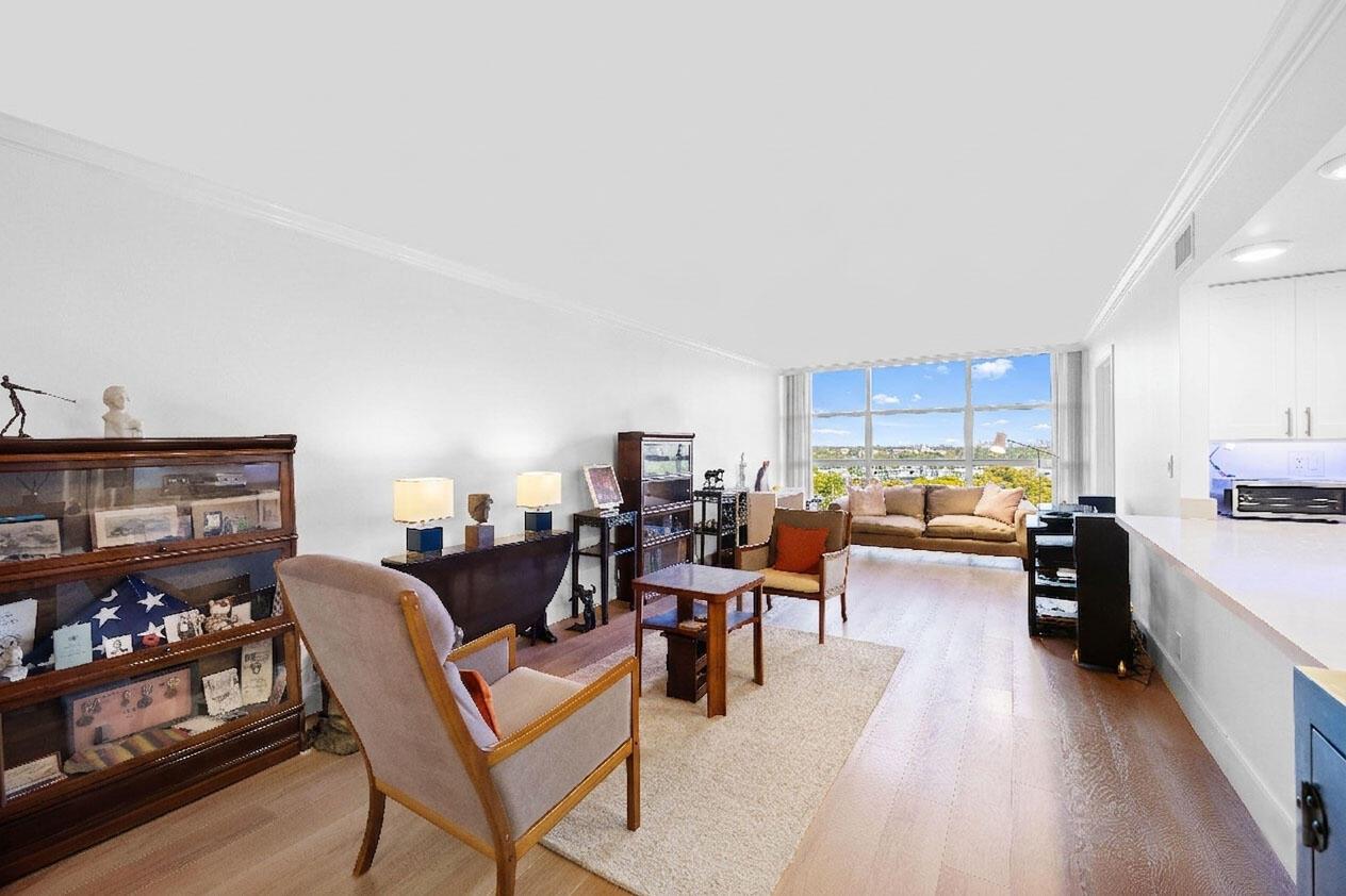 A bright living room with hardwood floors, a large window, and an open kitchen area — 600 Parkview Drive # 823, Hallandale Beach FL 33009, HALLANDALE BEACH, FL