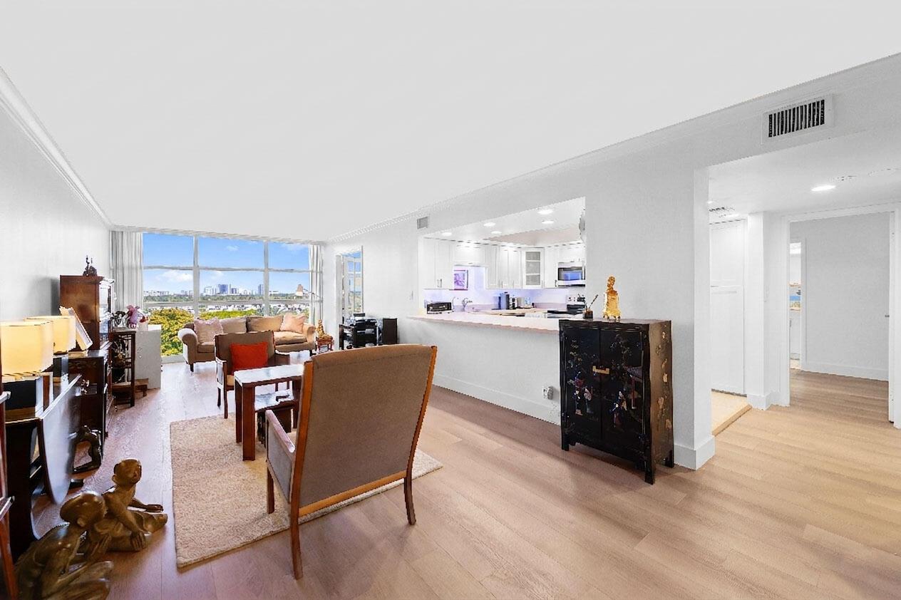 A living room with light wood floors, a kitchen pass-through, and floor-to-ceiling windows — 600 Parkview Drive # 823, Hallandale Beach FL 33009, HALLANDALE BEACH, FL
