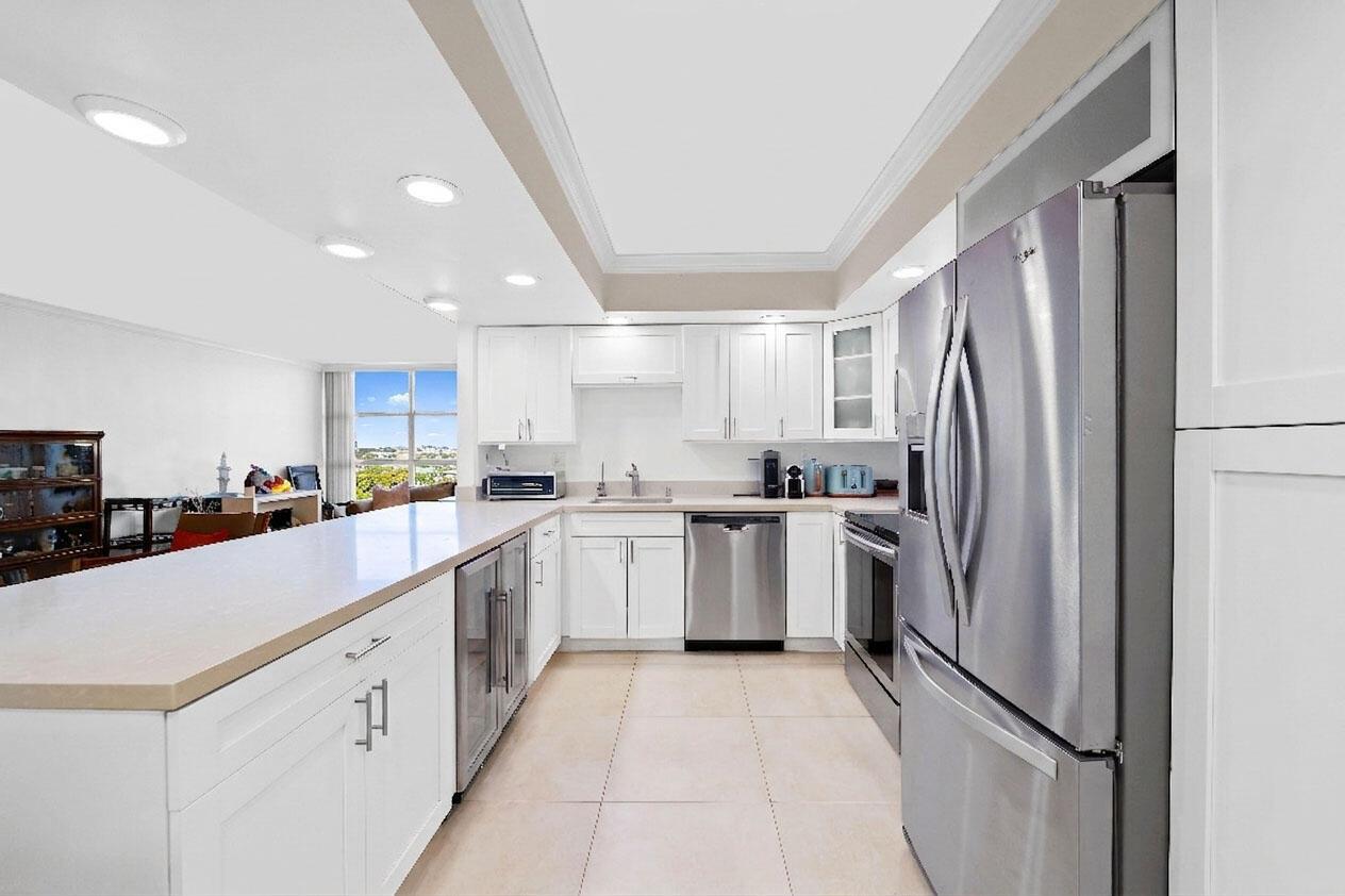 A modern kitchen features white cabinetry, stainless steel appliances, and a long breakfast bar — 600 Parkview Drive # 823, Hallandale Beach FL 33009, HALLANDALE BEACH, FL