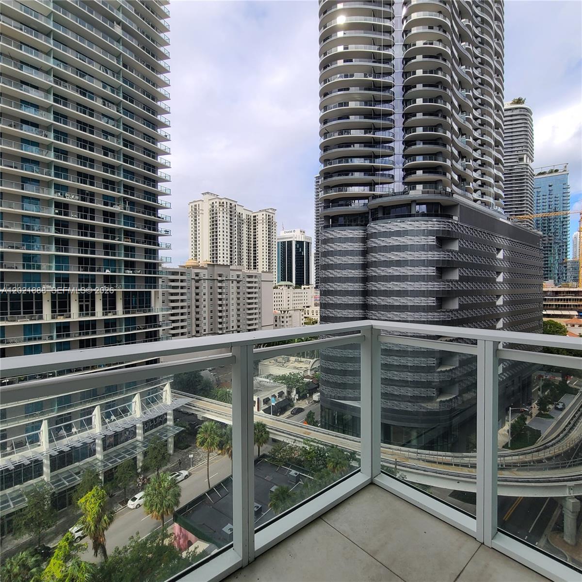 A balcony with a glass railing overlooks a city street and surrounding high-rise buildings — 1080 Brickell Ave # 1101, Miami FL 33131, MIAMI, FL