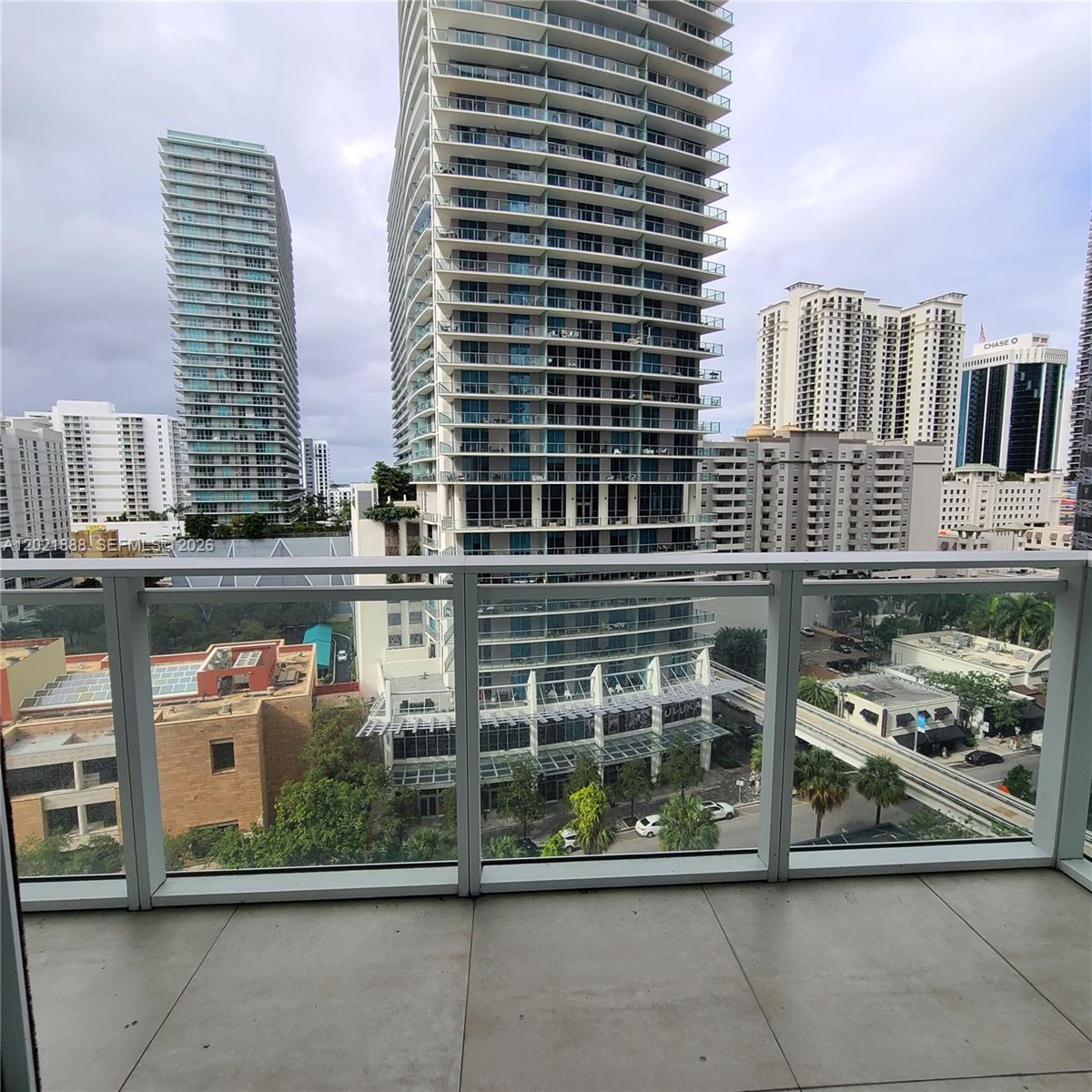 A balcony with glass railings overlooks a city street and several high-rise buildings — 1080 Brickell Ave # 1101, Miami FL 33131, MIAMI, FL